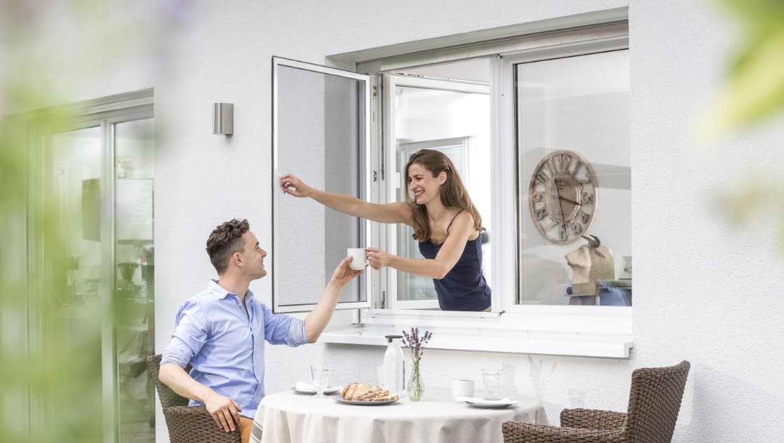 Drehrahmen am Fenster, draußen deckt jemand den Tisch