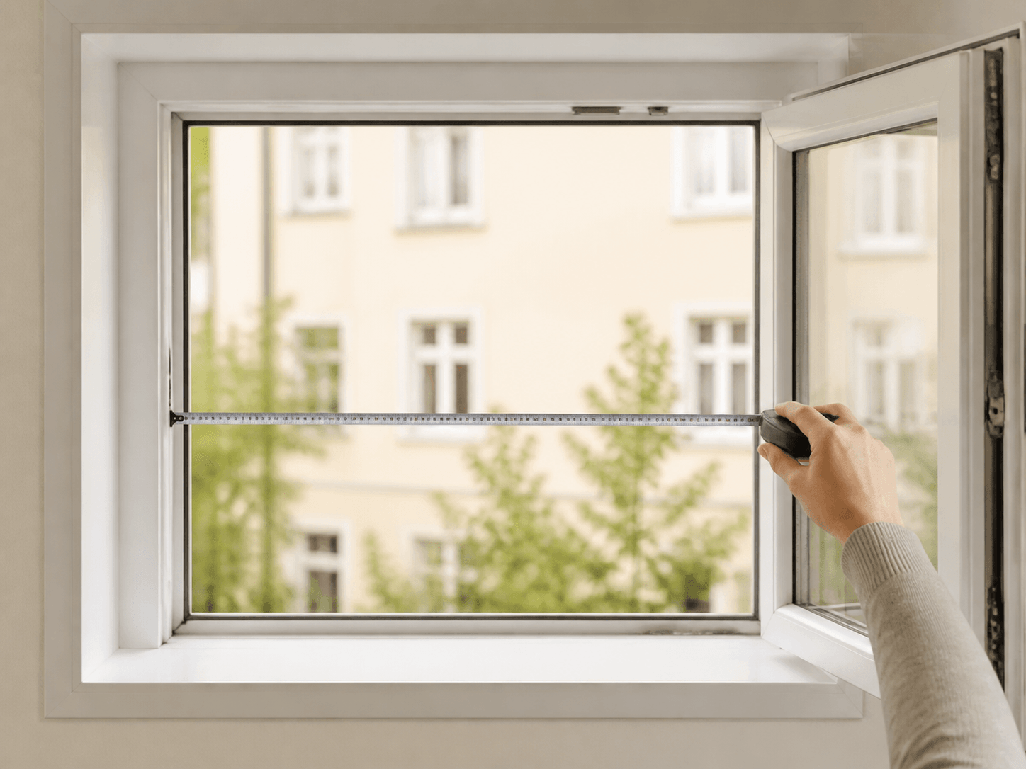 Hand misst die Breite im geöffneten Fenster